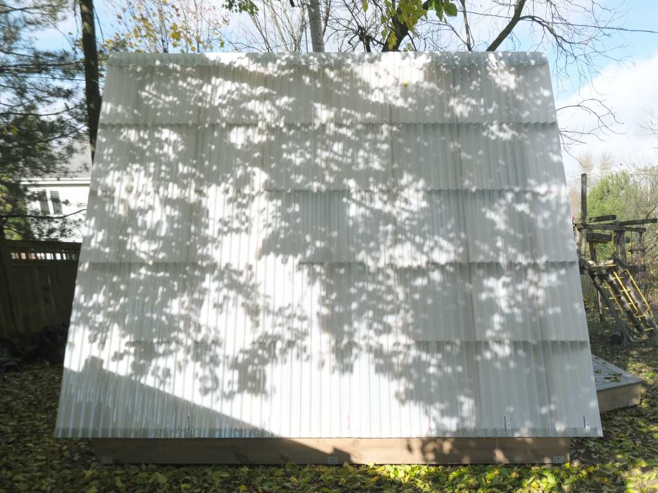 An overhead tree casts a summer-time shadow across the corrugated roof