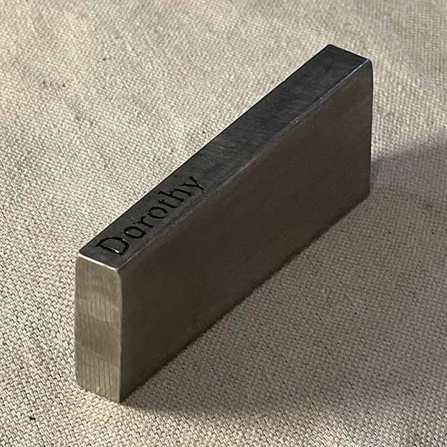 A stainless steel material sample with the name 'Dorothy' engraved in it