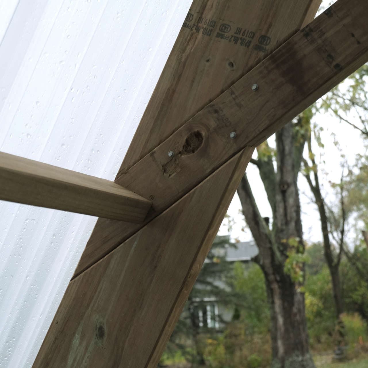 A closeup on the wood joinery supporting the roof, dappled with raindrops